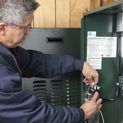 Lance Marques connects the thermostat power wire to the furnace