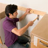 man affixing scrap lumber to the wall while preparing to install a glass mosaic backsplash