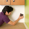 man preparing the wall to install a glass mosaic backsplash