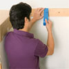 man marking a center line on the wall while preparing to install a glass mosaic backsplash