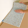 man laying out the tile sheets while preparing to install a glass mosaic backsplash