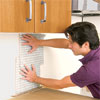 man laying out the remaining tile sheets while preparing to install a glass mosaic backsplash