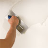 man coating a wall with thinset while preparing to install a glass mosaic backsplash