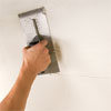 man combing the thinset while preparing to install a glass mosaic backsplash