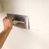 man smoothing the combed thinset while preparing to install a glass mosaic backsplash