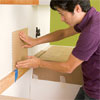 man placing the first tile sheet to install a glass mosaic backsplash