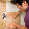 man installing the rest of the tile sheets for a glass mosaic backsplash