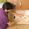 man setting a consistent depth for the tile sheets of a glass mosaic backsplash