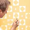 man using paint brush to fill in the thin spots after using a stamp to create a decorative pattern