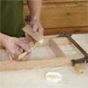 hands brushing glue onto the spindles for building a dog gate