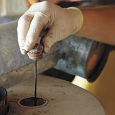 a latex-gloved hand lifts an anode rod that is way overdue for replacement from a water heater