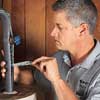man insulating pipes coming from a water heater with self-sticking foam pipe insulation