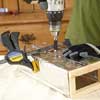 gloved hands nailing tin to wooden box
