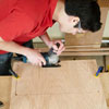 Mark Powers uses a jigsaw to cut out the back window of a dog crate