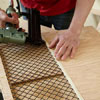 Mark Powers attaches the grille to the side windows for a side panel of a dog crate