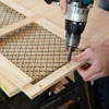 Mark Powers drills pilot holes into the side panel of a dog crate