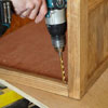 Mark Powers drills a hole for one of the pivot hinges inside the face frame of a dog crate
