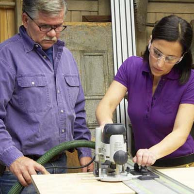 Tom Silva and Amy Paladino use a router to make [FRACTION 12]-inch slots for plywood shelves