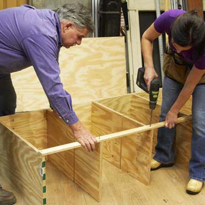 Tom Silva and Amy Paladino install the rail for the tool bench outer frame