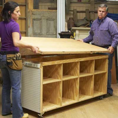 Tom Silva and Amy Paladino install the work surface area onto the top of the tool bench