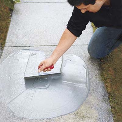 trowelling the concrete resurfacer on the walkway in order to spread evenly