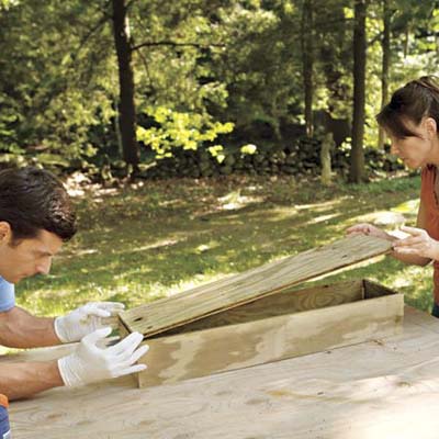 man and woman attaching bottom of window box frame