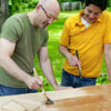 two people applying a clear coat of polyurethane to one side of a door