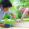 two men assembling frames for cornhole game board