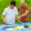 two men painting design for cornhole game board