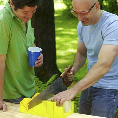 man using handsaw to cut grooves on kubb pieces