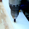 people drilling holes in the sides of the boards while building a ricochet game board