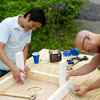 two men attaching legs for cornhole game board