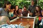 group of happy people standing around a team saturday ricochet game board