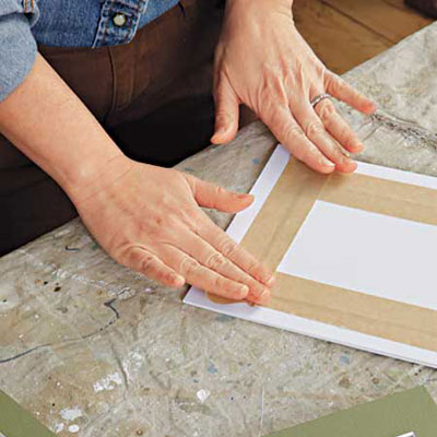 woman secures the photos to the back of mat with paper tape