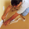 two people using a wide-blade carpet chisel to demonstrate how-to install carpet
