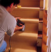 person tacking carpet to a tread to demonstrate how-to install carpet