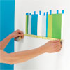 hands measuring a completed pattern to repeat when painting a striped wall