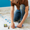person creating a story stick to help orient someone painting a striped wall