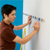 person using a story stick to mark the wall where stripes will be painted