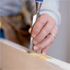 hand using a chisel to fix a stuck door