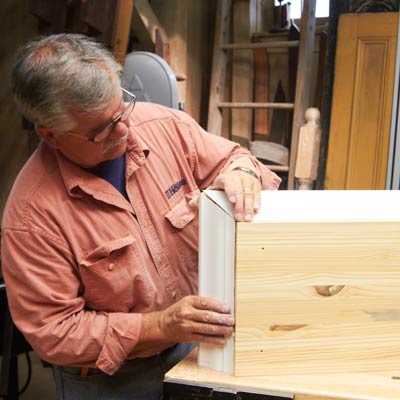 Tom Silva attaches trim to the top of the shelving unit