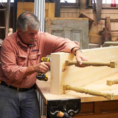 Tom Silva screwing spindles to the base of the shelving unit
