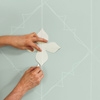man using paper template to create painted wall design
