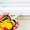 man covering screwheads on new windowsill with white adhesive
