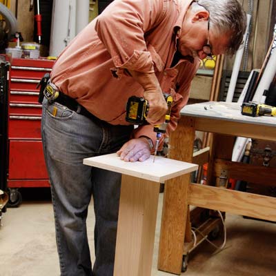 Tom Silva attaches a leg plate to the table leg for a trestle table with a drill/driver