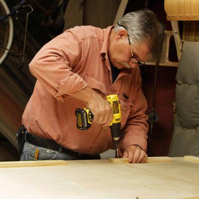 Tom Silva attaches cleats to the underside of the table top for a trestle table with a drill/driver