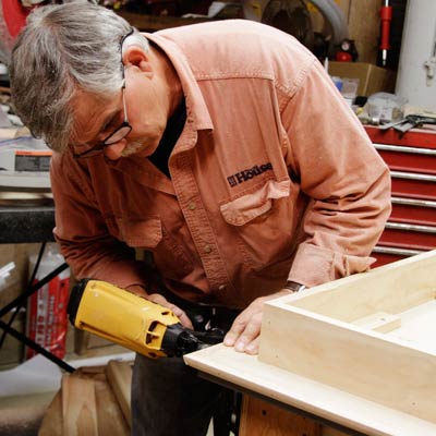 Tom Silva attaches 1/4-inch trim to the edges of the table top for a trestle table