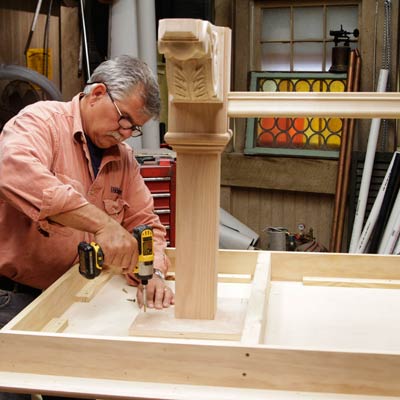 Tom Silva attaches the leg assembly to the underside of the table top for a trestle table