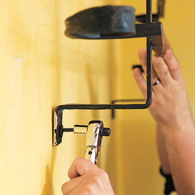 using a ratchet wrench to screw in lag bolts that will hold up a pot rack