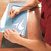 Mark Powers cuts the curved lines of the stencil pattern with an electric stencil-cutting pen
